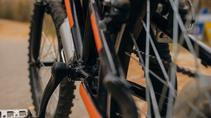 One caucasian children walk with bike in autumn park. Little girl walking black orange cycle in forest. Kid goes do bicycle sports. Biker motion ride with backpack and helmet. Mountain bike hardtail.