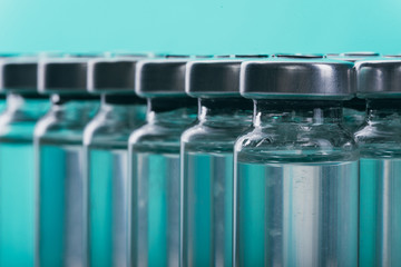 Glass medical ampoule vial for injection. Medicine is liquid sodium chloride with of aqueous solution in ampulla. Close up. Bottles ampule multicolor on background color and water. Human plasma.