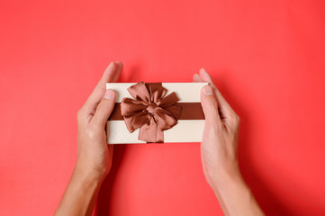 Holding a gift box on a red background.