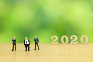 Fototapeta premium Miniature people - businessman greeting for happy new year 2020 with dreamy green background