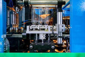 The production of PET bottles in the automatic blowing machine for drinking water factory. The operation of PET bottle processing by blowing process with the blowing mold.