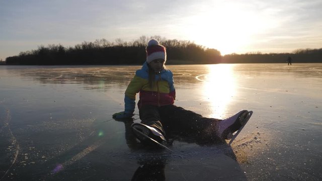 A little girl enjoying ice skating at frozen lake in winter season. Winter sports.