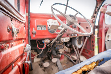 Old worn out, rustic red tractor interior with broken parts and exposed driver area