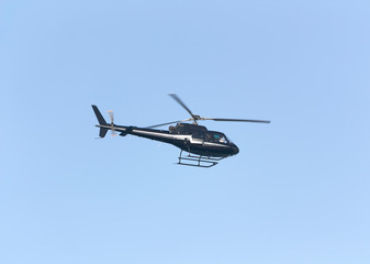 Black passenger helicopter on blue sky background
