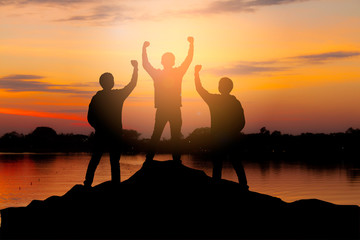 Silhouette of happy teamwork hold hands up as a successful, victory and achieve a business goal in...