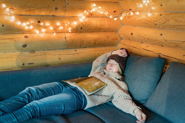 Sleeping in warm house on cozy sofa in log cabin in cold winter.