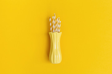 Minimal composition yellow colored with paper drinking straws inside ceramic vase. Creative trendly concept for holiday, birthday greeting card. Top view and flat lay.