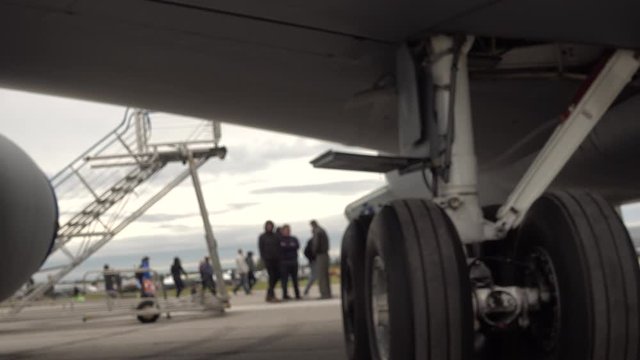 Closeup Of Aircraft Landing Gear With People Walking In Background Slightly Blurred At Airshow 002