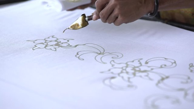 Close-up video of a process of making written batik. Batik is a technique of wax-resist dyeing applied to whole cloth, or cloth made using this technique, originated from thailand