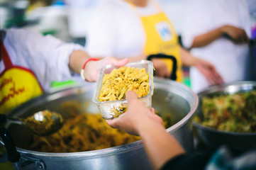 The hands of the poor receive food that volunteers share to alleviate hunger: the concept of donating food to the poor