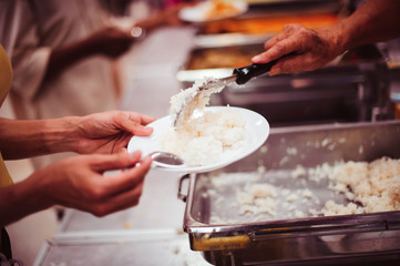 Food donation to the poor: The hands of the homeless are waiting to receive food from volunteers.