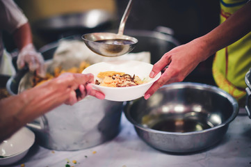Food donation to the poor: The hands of the homeless are waiting to receive food from volunteers.