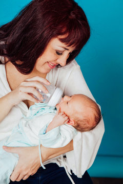 Mom Is Feeding The Baby Milk From A Bottle