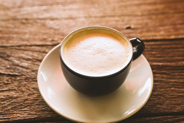 cup of coffee with cream on wooden background