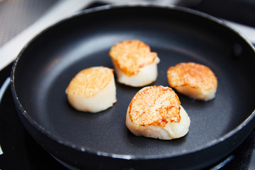 roasted scallops fried in a black pan, fried in oil, cooking, seafood