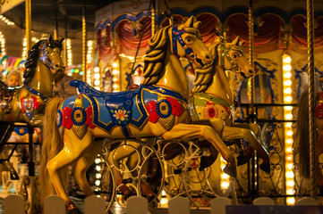 Fototapeta na wymiar Children's Carousel at an amusement park in the evening and night illumination. amusement park at night. Outdoor vintage colorful carousel in the the city / carousel detail.