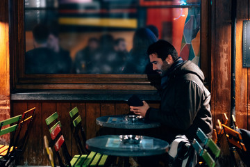 Fototapeta na wymiar one man sitting at a cafe terrace using mobile phone