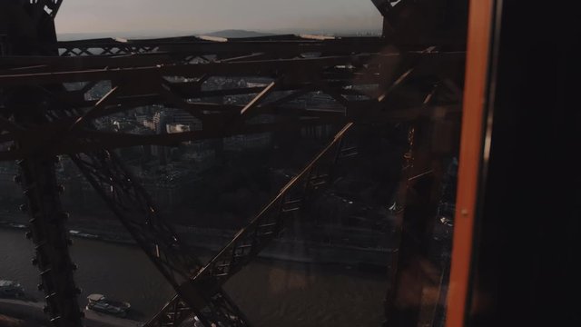 Cinematic background shot, camera is inside glass elevator moving up inside Paris Eiffel Tower steel structure bars.