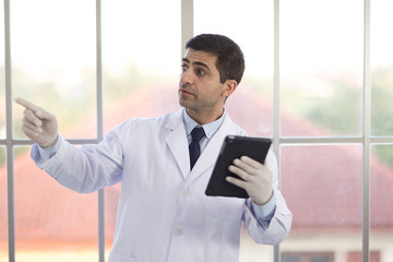 Fototapeta premium The male doctor wore a white robe and stood by the window in the laboratory.
