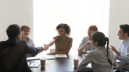 Fototapeta premium Diverse business partners gathered in boardroom shaking hands