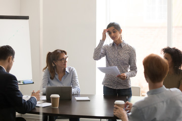 Indian presenter speaker stands in front of colleagues in meeting