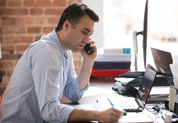 Serious businessman talking on phone having busy working day