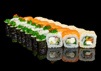 sushi and rolls with different fillings on a black background with reflection
