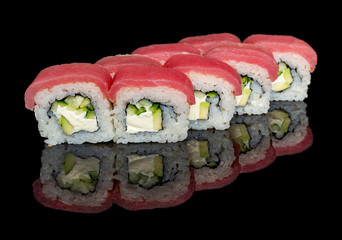 sushi and rolls with different fillings on a black background with reflection