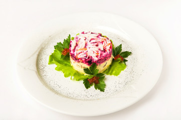 Fermented products in a restaurant close-up. Russian salad fur coat on a white plate and copy space. Herring under beets.