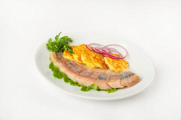 Fermented products in a restaurant close-up. Pickled herring with potato zrazy on a white plate and copy space.