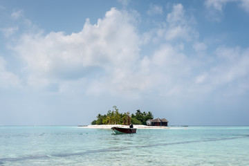 Landscape with a small island in the Maldives, Indian Ocean, Kaafu Atoll, Kuda Huraa Island. A motor boat is anchored in the foreground.
