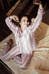 Fototapeta premium girl in pajamas woke up in the morning is sitting on a bed