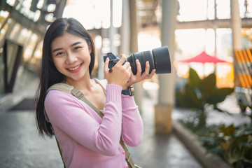 A young tourist is taking a picture with a camera and turning to smile.