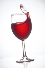 Glass of red wine on a light background, splashing wine, frozen motion