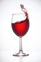 Glass of red wine on a glass table, splashing wine, frozen motion