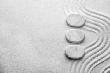 Fototapeta na wymiar Top view of white stones on sand with pattern, space for text. Zen, meditation, harmony