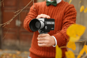 Young man with vintage video camera outdoors, closeup