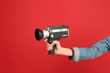 Woman with vintage video camera on red background, closeup of hand