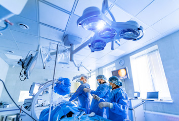 Medical team performing surgical operation in bright modern surgery room. Operating theatre. Modern...