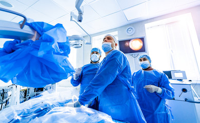 Team of surgeons performing operation in bright modern surgery room. Operating theatre. Modern...