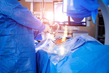 Surgeons perform spine surgery in modern operating room. Doctors making operation. Medical...