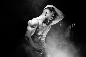 Strong brutal bodybuilder man with perfect abs, shoulders,biceps, triceps and chest showing his biceps. Scream motivation. Black and white.