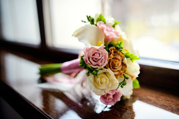 Gorgeous tender wedding bouquet with cream, ivory and pink roses on a windowsill. Closeup