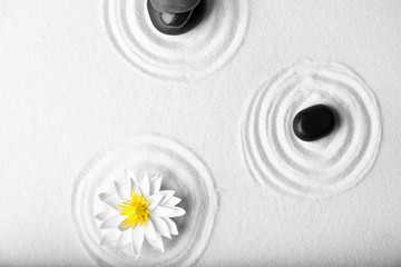 Zen garden. Beautiful lotus flower and stones on white sand, flat lay