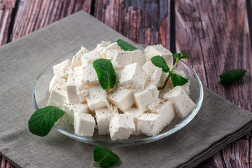 Sliced feta cheese with seasonings on a wooden table background