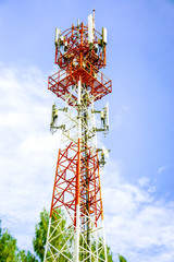 Telecoms tower with transmitter antenna on the bright blue sky background.