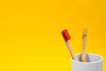 Toothbrushes made of bamboo in holder on yellow background. Space for text
