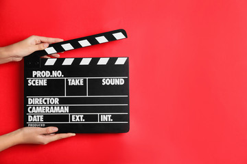 Woman holding clapperboard on red background, closeup with space for text. Cinema production