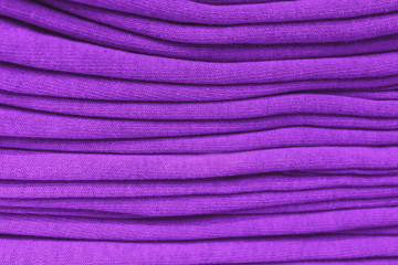Fototapeta na wymiar clothes stacked close-up, fabric texture, bright colors, neat purple violet stacks