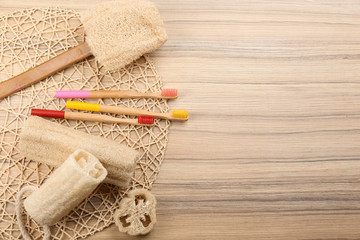Flat lay composition with natural bamboo toothbrushes on wooden table, space for text